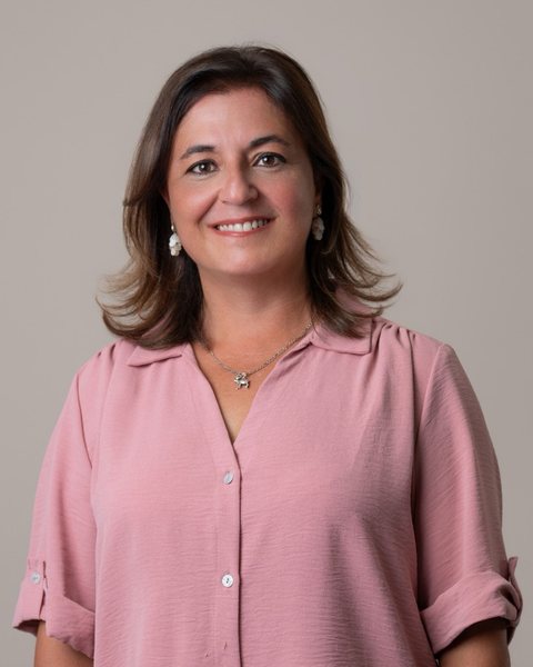 Idoia Salazar in a pink blouse, smiling, against a pale grey background.